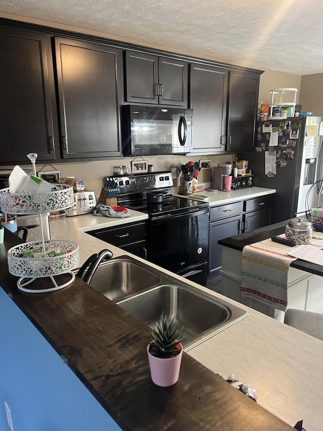 kitchen with a textured ceiling, black appliances, light countertops, and a sink