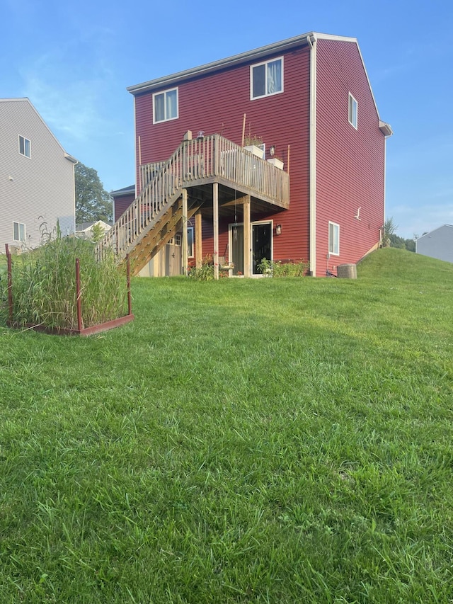 back of property with a lawn, a wooden deck, and stairs