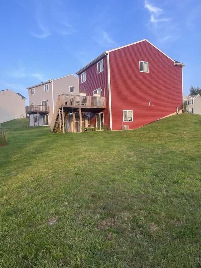 back of house with a deck, stairs, and a lawn