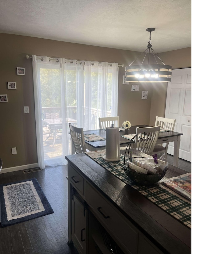 dining room with a chandelier, a textured ceiling, plenty of natural light, and dark wood-type flooring