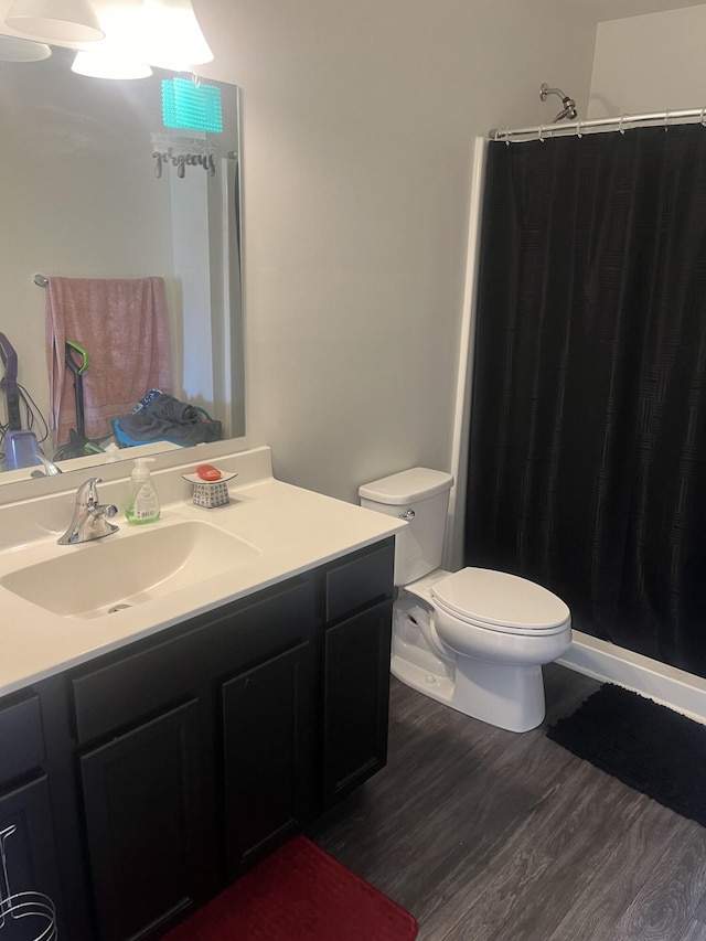 full bathroom featuring curtained shower, toilet, wood finished floors, and vanity