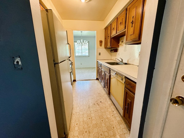 kitchen with sink, dishwasher, light tile patterned floors, and an inviting chandelier