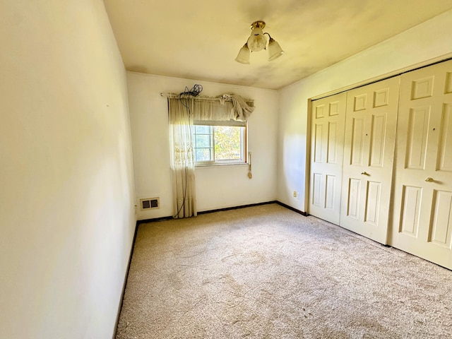 unfurnished bedroom with light carpet and a closet