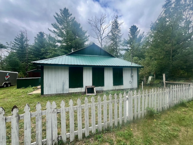 view of home's exterior featuring an outbuilding, fence, and metal roof