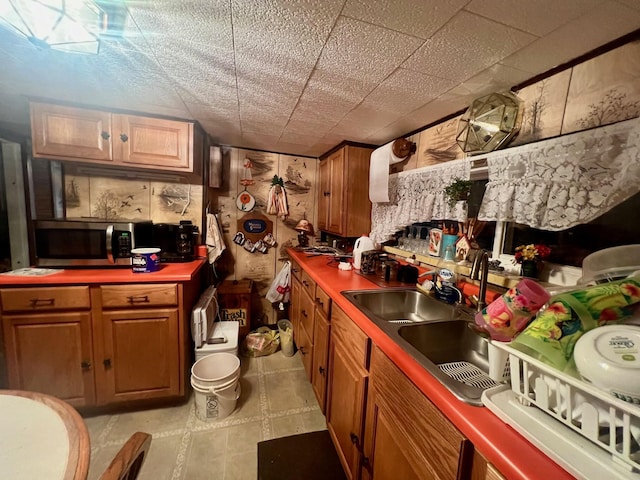 kitchen featuring stainless steel microwave, brown cabinets, and a sink