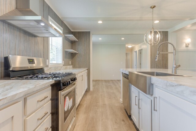 kitchen featuring light wood-type flooring, stainless steel appliances, white cabinetry, and wall chimney range hood