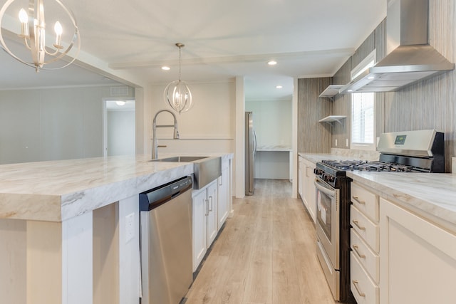 kitchen with light hardwood / wood-style flooring, appliances with stainless steel finishes, wall chimney range hood, decorative light fixtures, and sink