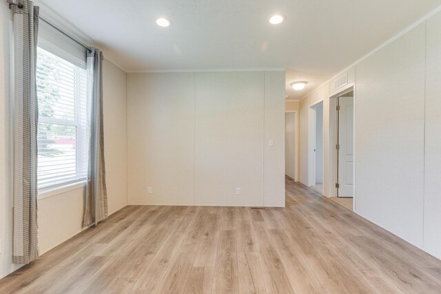 spare room featuring crown molding and light hardwood / wood-style floors