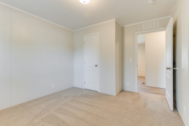 unfurnished bedroom with ornamental molding, a closet, and light colored carpet