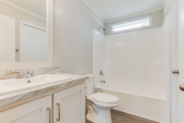 full bathroom featuring toilet, ornamental molding, hardwood / wood-style flooring, bathing tub / shower combination, and vanity