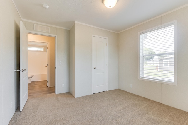 unfurnished bedroom featuring light carpet, crown molding, and a closet