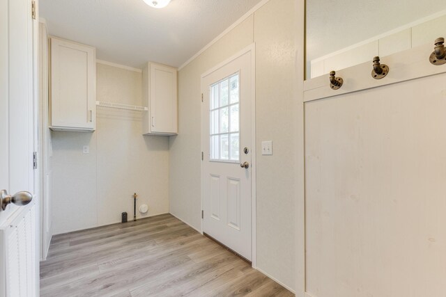 laundry room featuring crown molding and light hardwood / wood-style floors