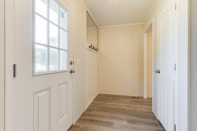 doorway to outside with light hardwood / wood-style floors and crown molding