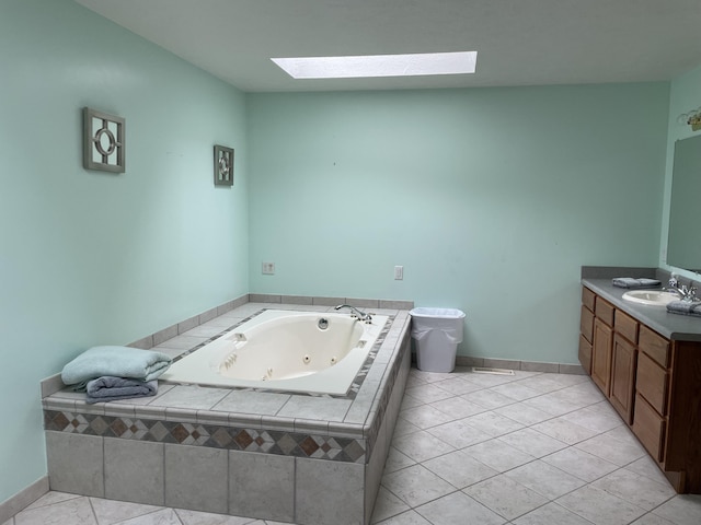 bathroom featuring a jetted tub, baseboards, a skylight, tile patterned floors, and vanity