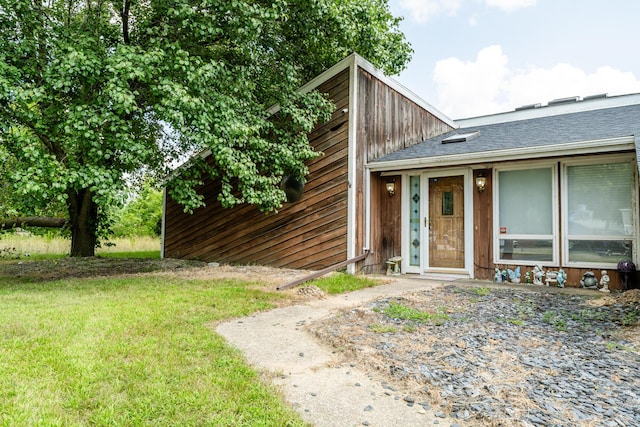 view of front of home with a shingled roof and a front yard