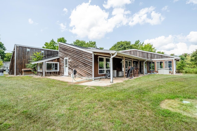 rear view of property featuring a patio and a lawn