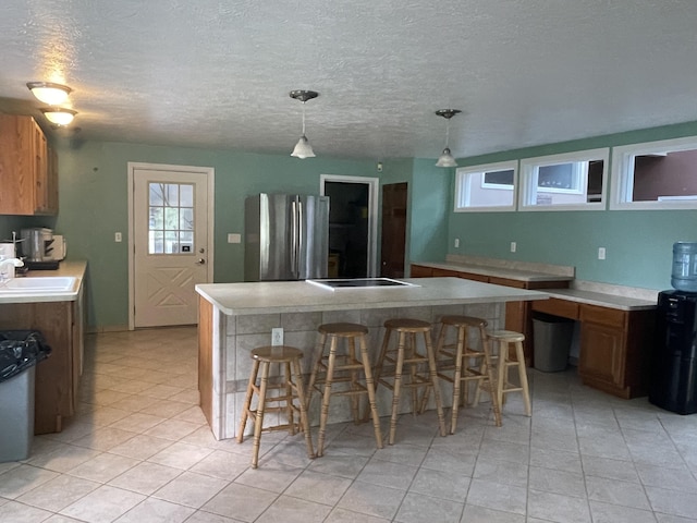 kitchen featuring a kitchen bar, light countertops, freestanding refrigerator, and a center island