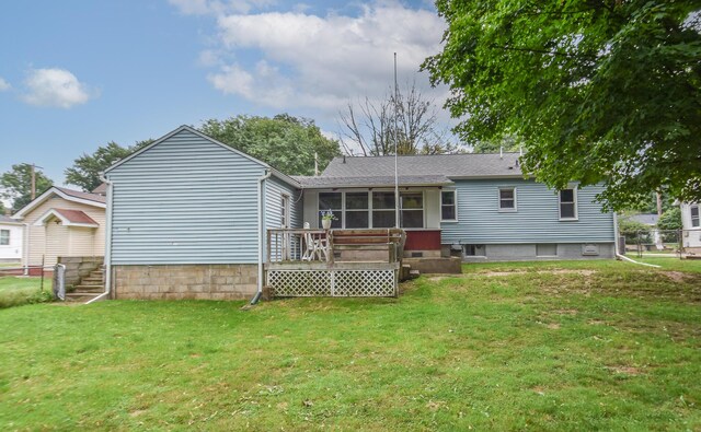 rear view of property with a lawn, a wooden deck, and a sunroom