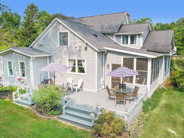 rear view of house with a sunroom, a yard, and a deck