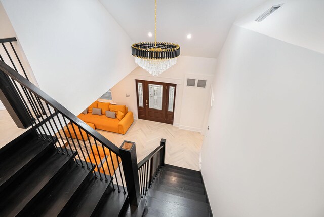 stairway with parquet flooring and an inviting chandelier