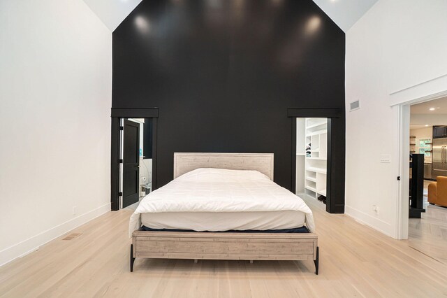 bedroom featuring high vaulted ceiling and light hardwood / wood-style floors