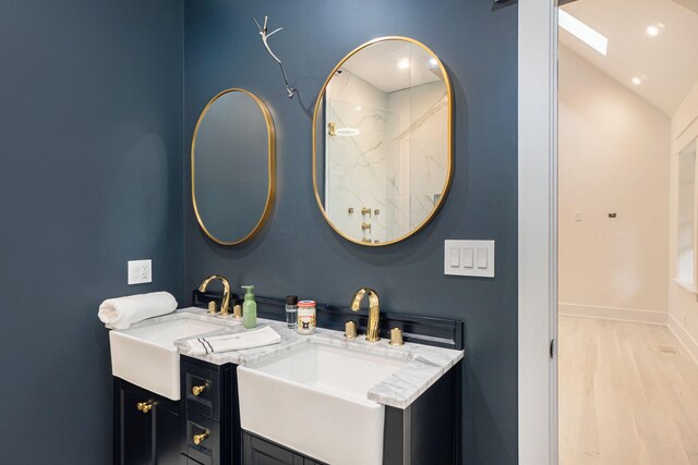 bathroom featuring dual vanity, wood-type flooring, and lofted ceiling