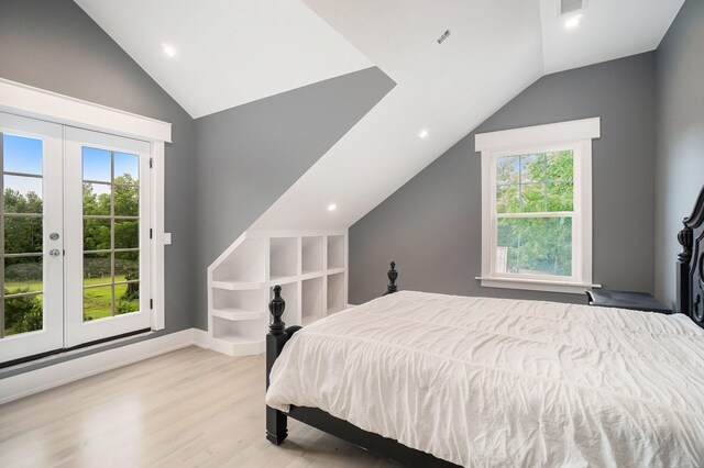 bedroom featuring light wood-type flooring, vaulted ceiling, french doors, and multiple windows