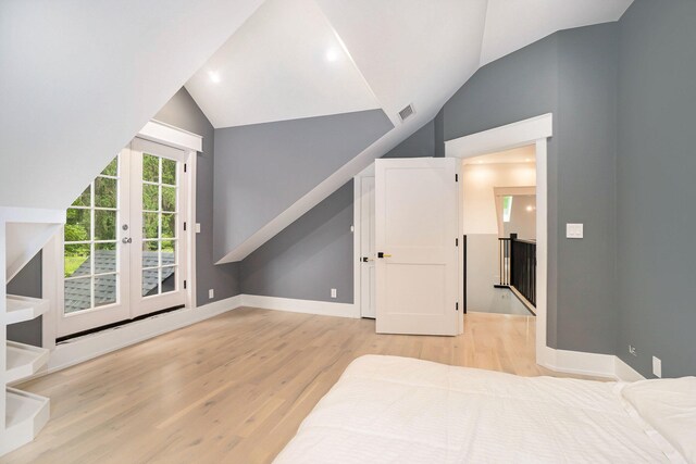 bedroom with light hardwood / wood-style floors, french doors, and lofted ceiling