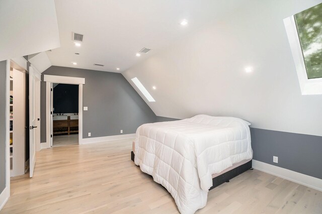 bedroom featuring light hardwood / wood-style floors and lofted ceiling with skylight