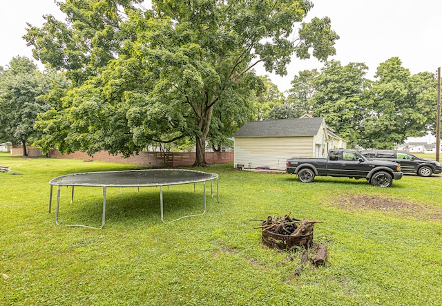 view of yard featuring an outdoor fire pit and a trampoline