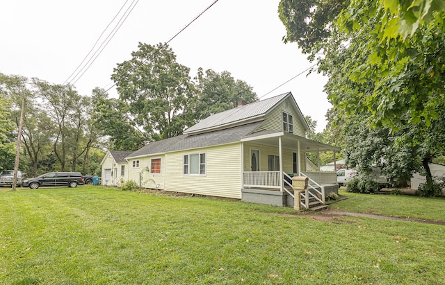 rear view of house featuring a yard and covered porch