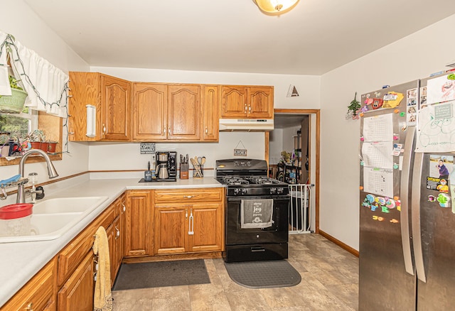 kitchen with sink, black gas stove, light tile patterned flooring, and stainless steel refrigerator