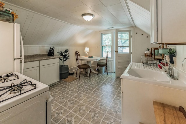 kitchen with sink, tile patterned floors, white appliances, vaulted ceiling, and white cabinetry