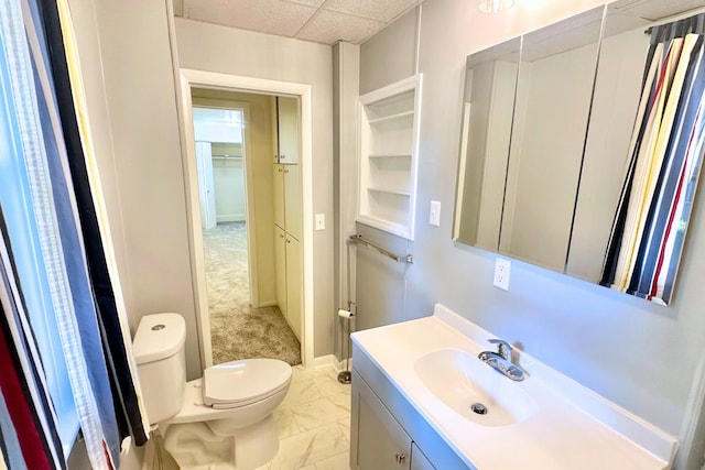 bathroom featuring a drop ceiling, toilet, vanity, and tile patterned floors