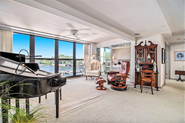 sitting room with ceiling fan, light carpet, and a water view