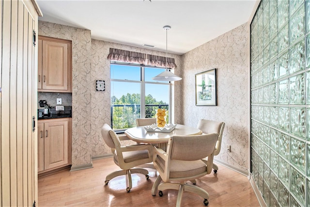 dining space featuring visible vents, light wood-style flooring, and wallpapered walls