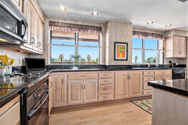 kitchen featuring black appliances, light brown cabinets, a sink, backsplash, and light wood finished floors