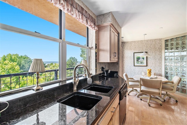 kitchen with sink, dark stone countertops, light hardwood / wood-style floors, dishwasher, and hanging light fixtures