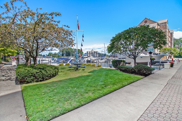 view of home's community featuring a yard, a boat dock, and a water view