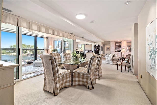 carpeted dining space featuring a wealth of natural light and a water view