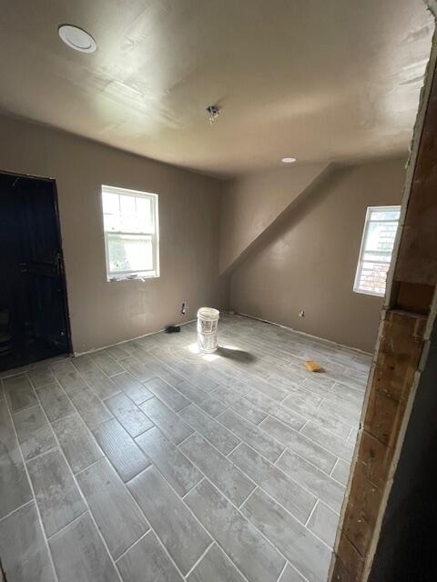 additional living space featuring plenty of natural light, lofted ceiling, and wood-type flooring