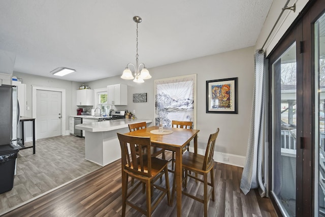 dining space featuring sink, a chandelier, dark hardwood / wood-style floors, and plenty of natural light