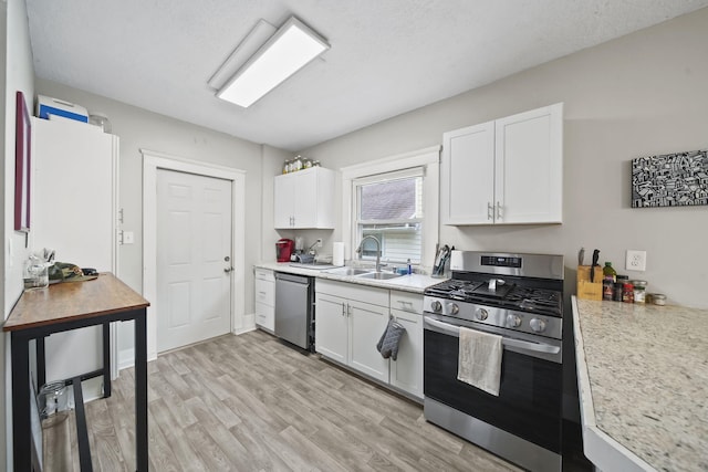 kitchen with stainless steel appliances, sink, and white cabinets