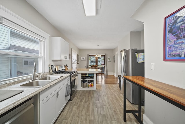 kitchen with hanging light fixtures, white cabinetry, light hardwood / wood-style flooring, sink, and stainless steel appliances