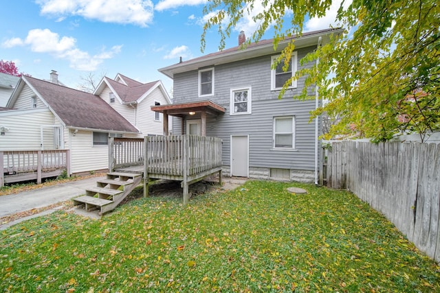 rear view of property featuring a deck and a lawn