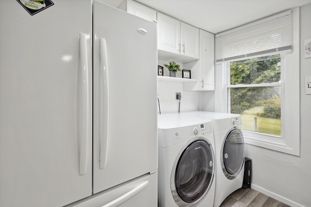 laundry area with a wealth of natural light, light hardwood / wood-style floors, independent washer and dryer, and cabinets