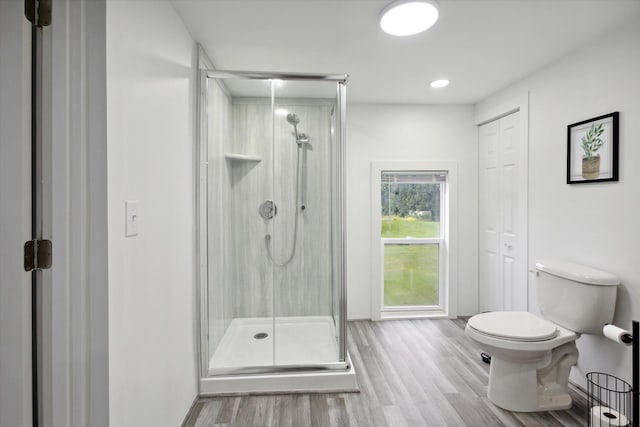 bathroom with hardwood / wood-style floors, toilet, and a shower with shower door