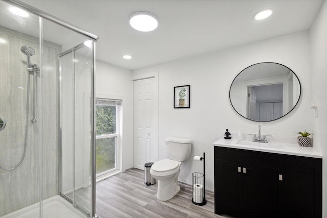 bathroom featuring hardwood / wood-style flooring, toilet, walk in shower, and vanity