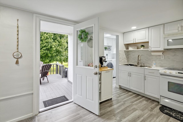 kitchen with backsplash, white cabinets, light hardwood / wood-style floors, sink, and white appliances