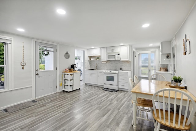 kitchen with light hardwood / wood-style floors, stove, plenty of natural light, and white cabinets